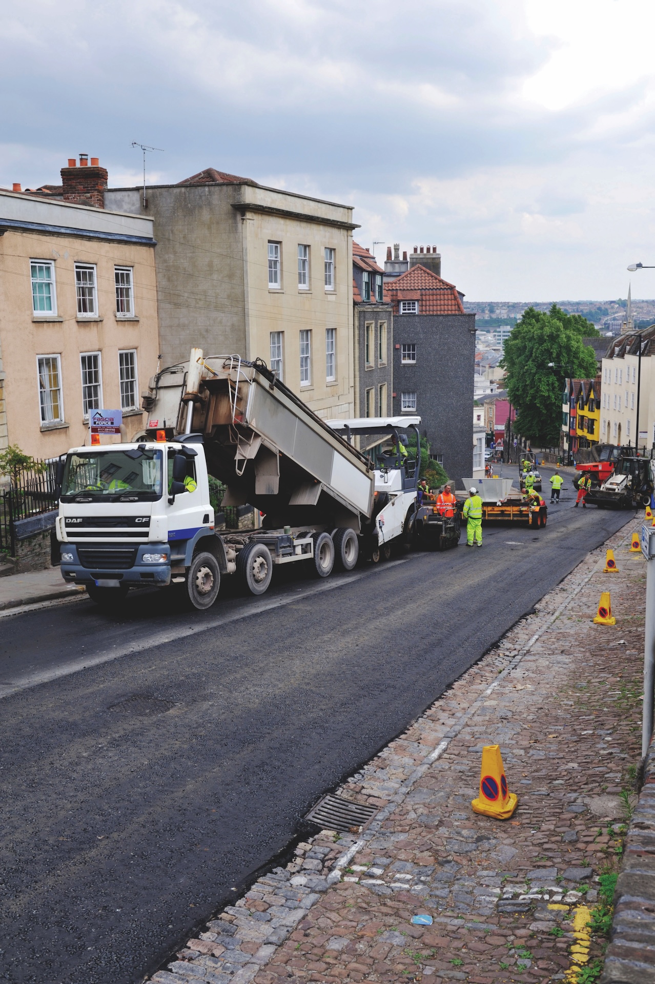 Road Works, Asphalt Spreading Machine Being Loaded With Asphalt From Dumper Truck For Road Resurfacing UK